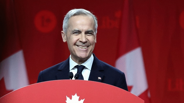An aged Caucasian male smiles at a podium
